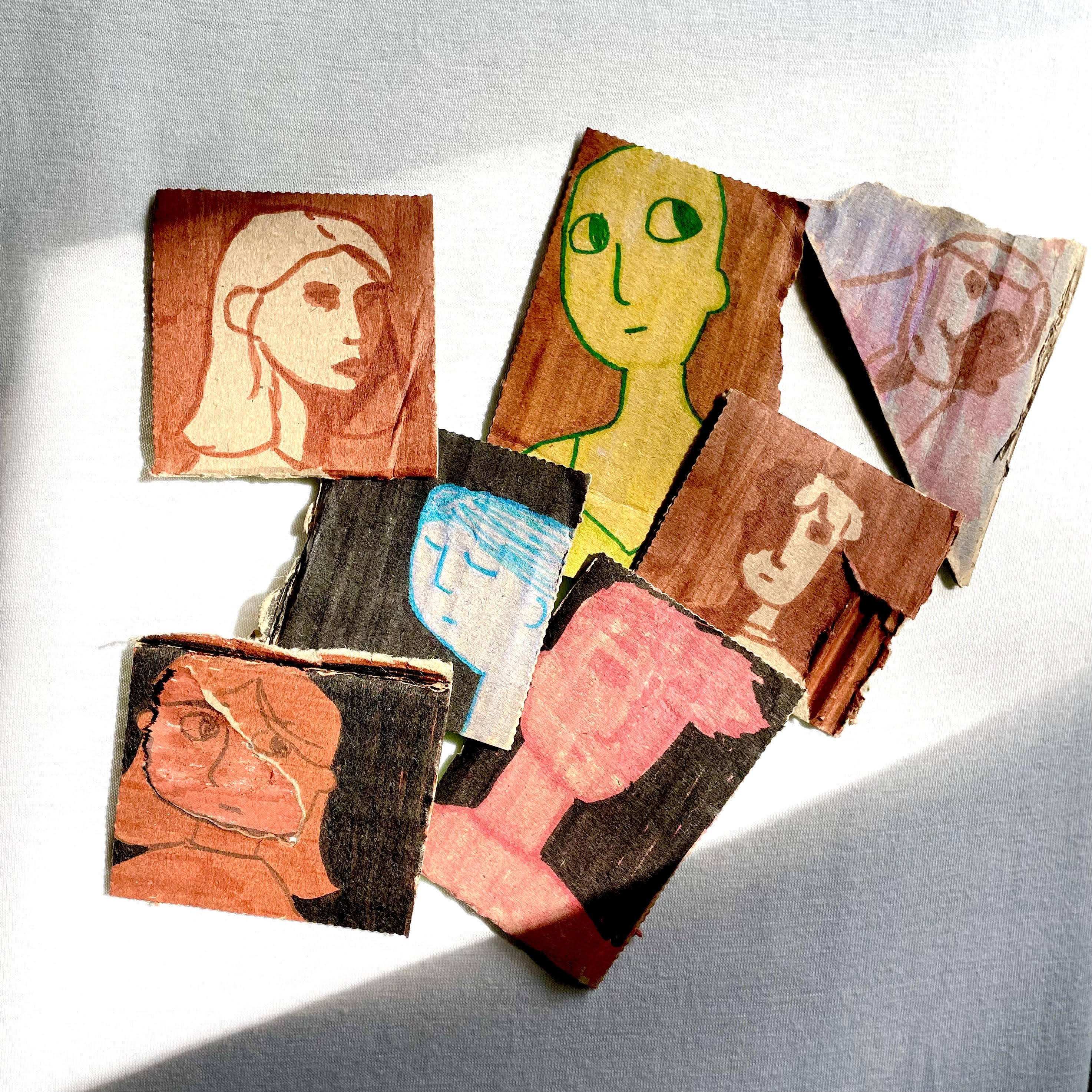 Multiple drawings on small pieces of cardboard, put together for a photo.